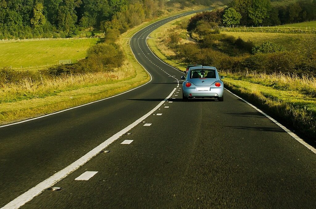 Auto jedoucí po silnici směrem k lesu.