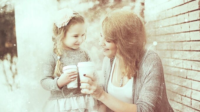 Matka s dcerou mají kávu v platovém kelímku při procházce.