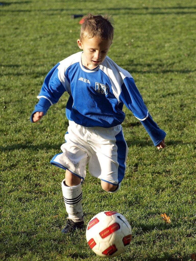 Malý kluk hraje fotbal.