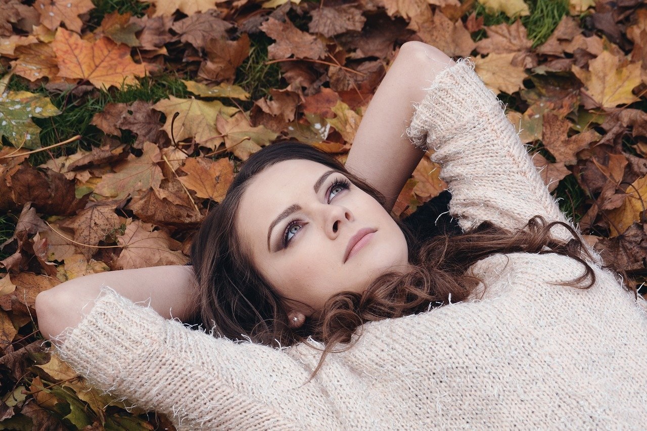 Dívka s kaštanovými vlasy, leží v podzimním listí