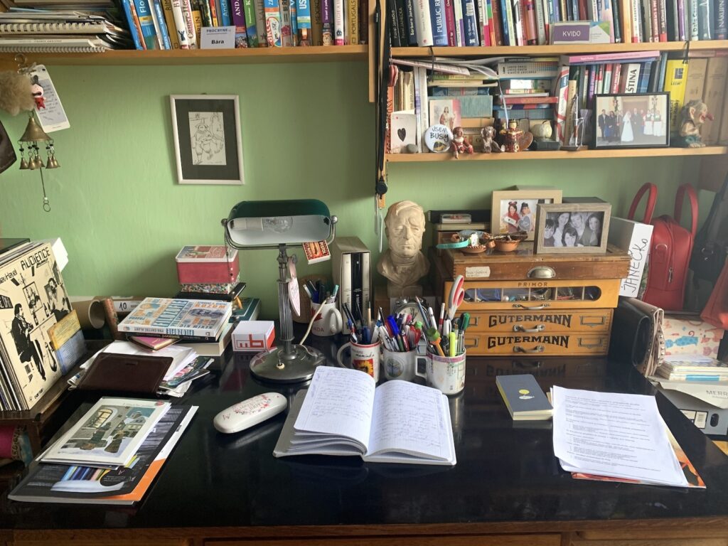 Psací stůl na kterém je spoustu psacích potřeb a deník