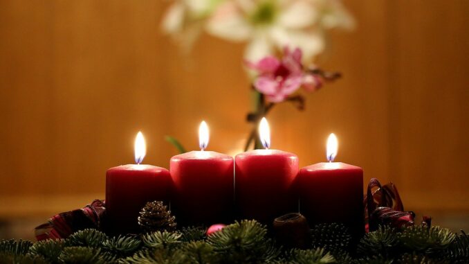 Adventní věnec se čtyřmi zapálenými svíčkami.