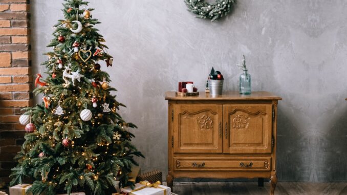 Vánoční stromeček s dárky zelený věnec na stěně a stará komoda