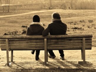 Dva lidí sedí v zimě na laviččce.