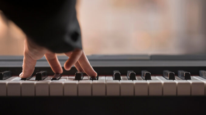Detail ruky hrající na klavír.