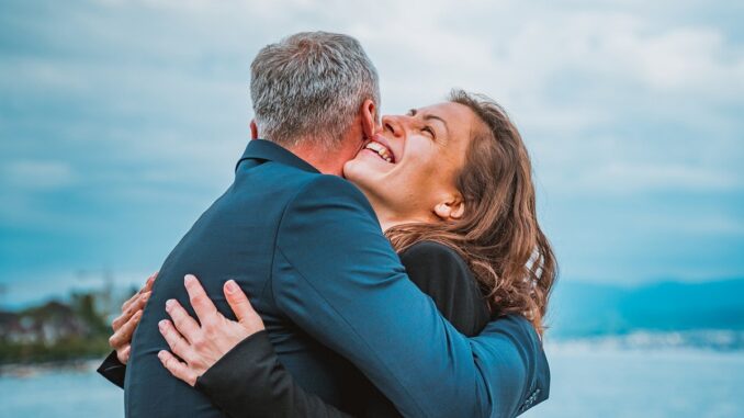 Muž a smějící se žena se objímají.