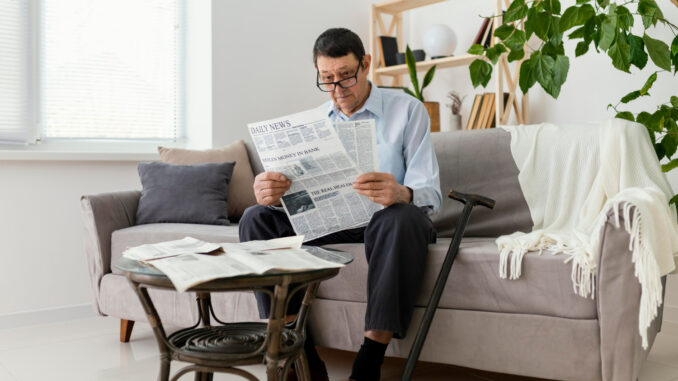 Muž na gauči si čte noviny.