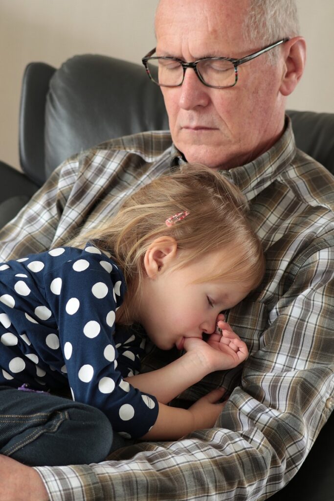 Vnouče spí u dědečka na klíně.
