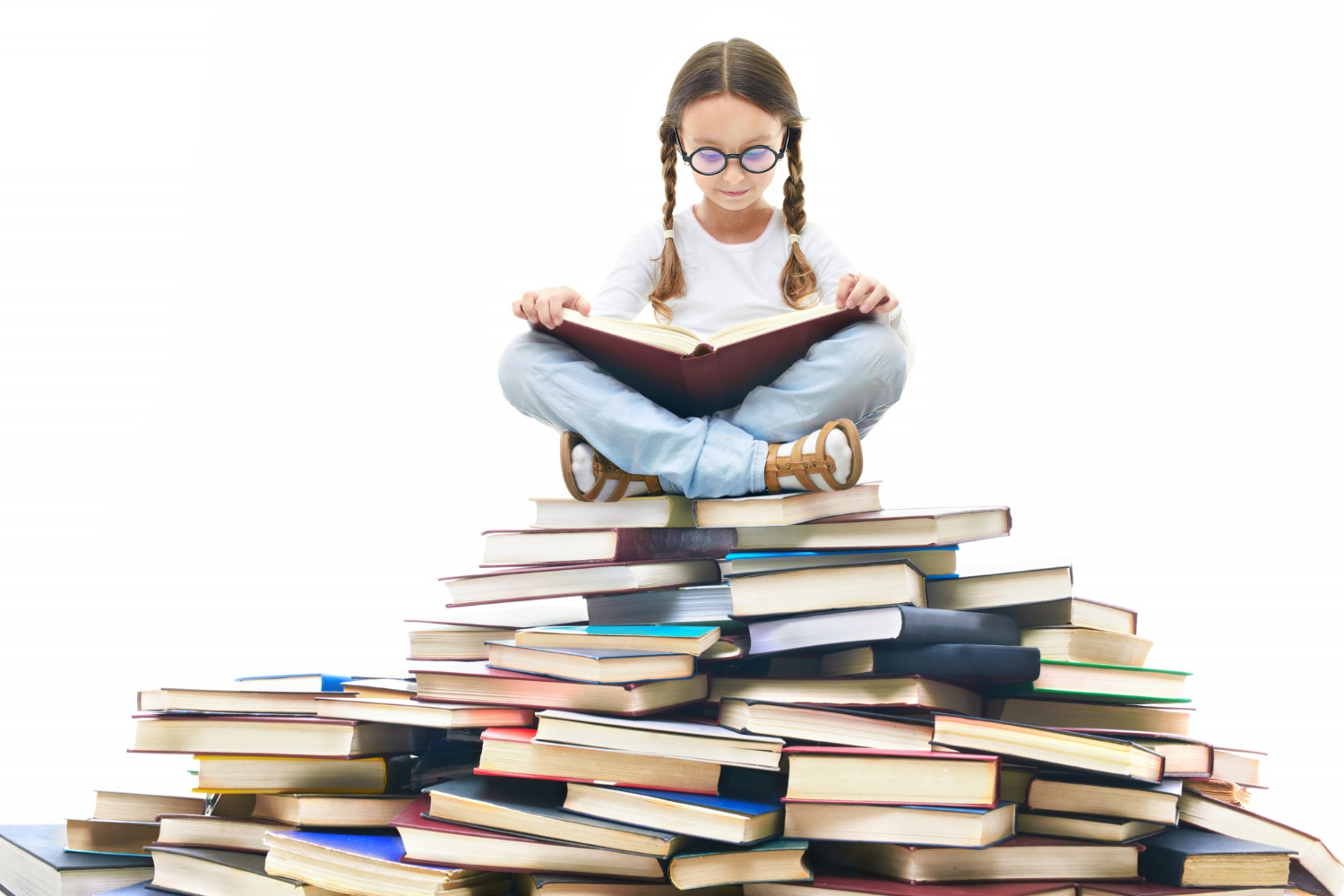 Dívka sedí na hromadě knih.