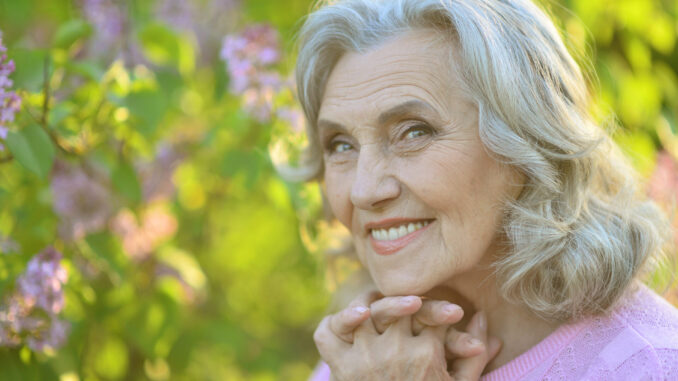 Beautiful senior woman posing near blooming tree