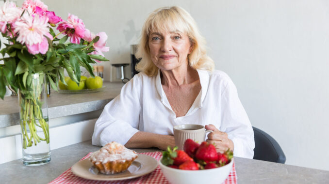 Happy mature lady sitting with cup of coffee