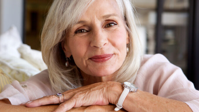 relaxed older woman smiling and sitting on sofa