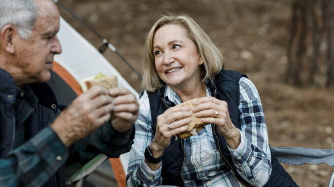 Romantic senior couple having a picnic by the campsite