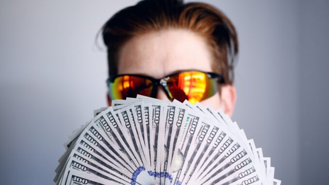 Photo by Shane man in black framed sunglasses holding fan of white and gray striped cards