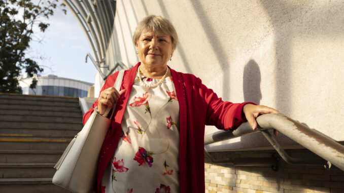 Portrait Elder Mature Lady In Casual Clothes Moving Downstairs In Underground Crossing. Smiling Beautiful Elegant Real Female With Gray Hair Holds Railing. Retirement. Horizontal Plane