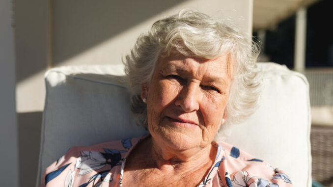 Portrait of senior caucasian woman sitting on balcony looking at camera. retreat, retirement and happy senior lifestyle concept.