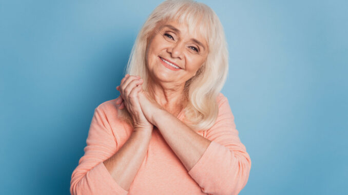 Portrait of sincere old woman on blue background