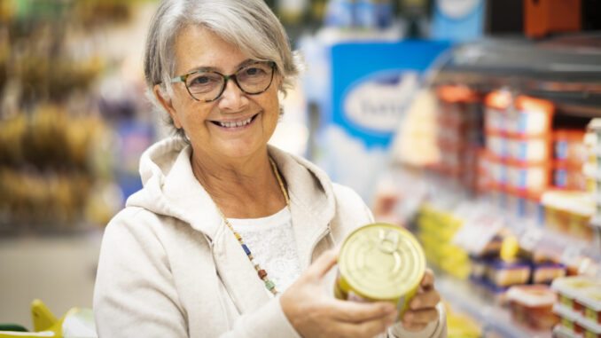 Happy smiling senior woman at the supermarket reading carefully