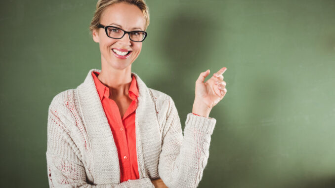 Teacher showing at blackboard at school