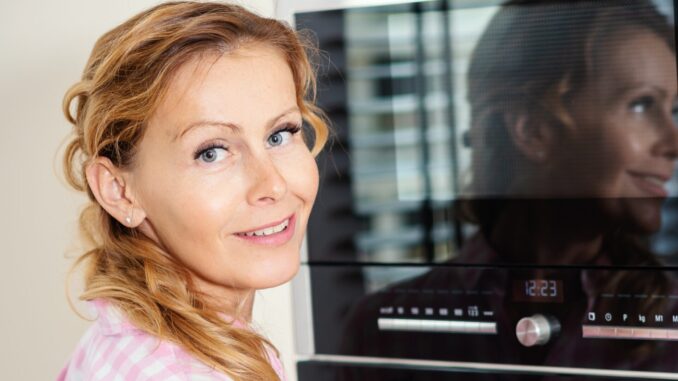 woman turning on the oven in the kitchen