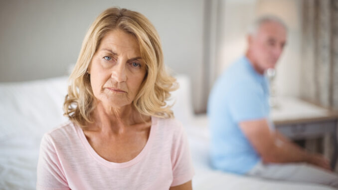 Senior couple ignoring each other on bed in bedroom at home