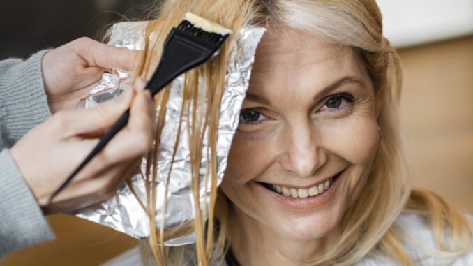 smiley-woman-getting-her-hair-dyed-by-hairdresser-home