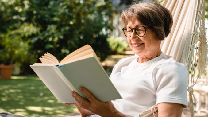 Happy relaxed old senior elderly woman grandmother relaxing while reading book
